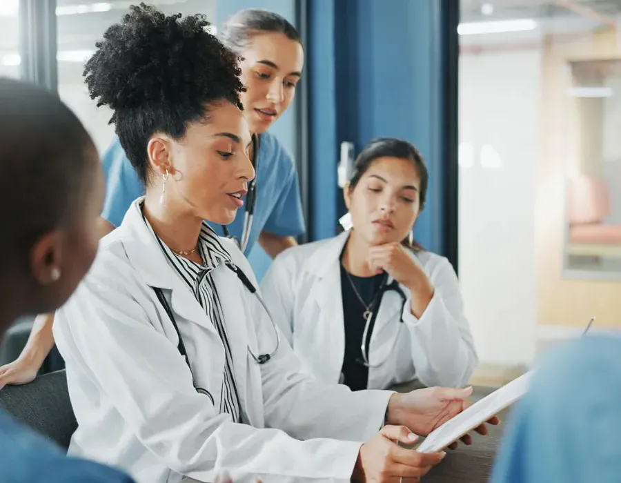 Healthcare manager in white coat leading team discussion in hospital conference room